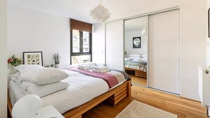A modern bedroom with a wooden bed, a large mirror, and a sliding door closet.