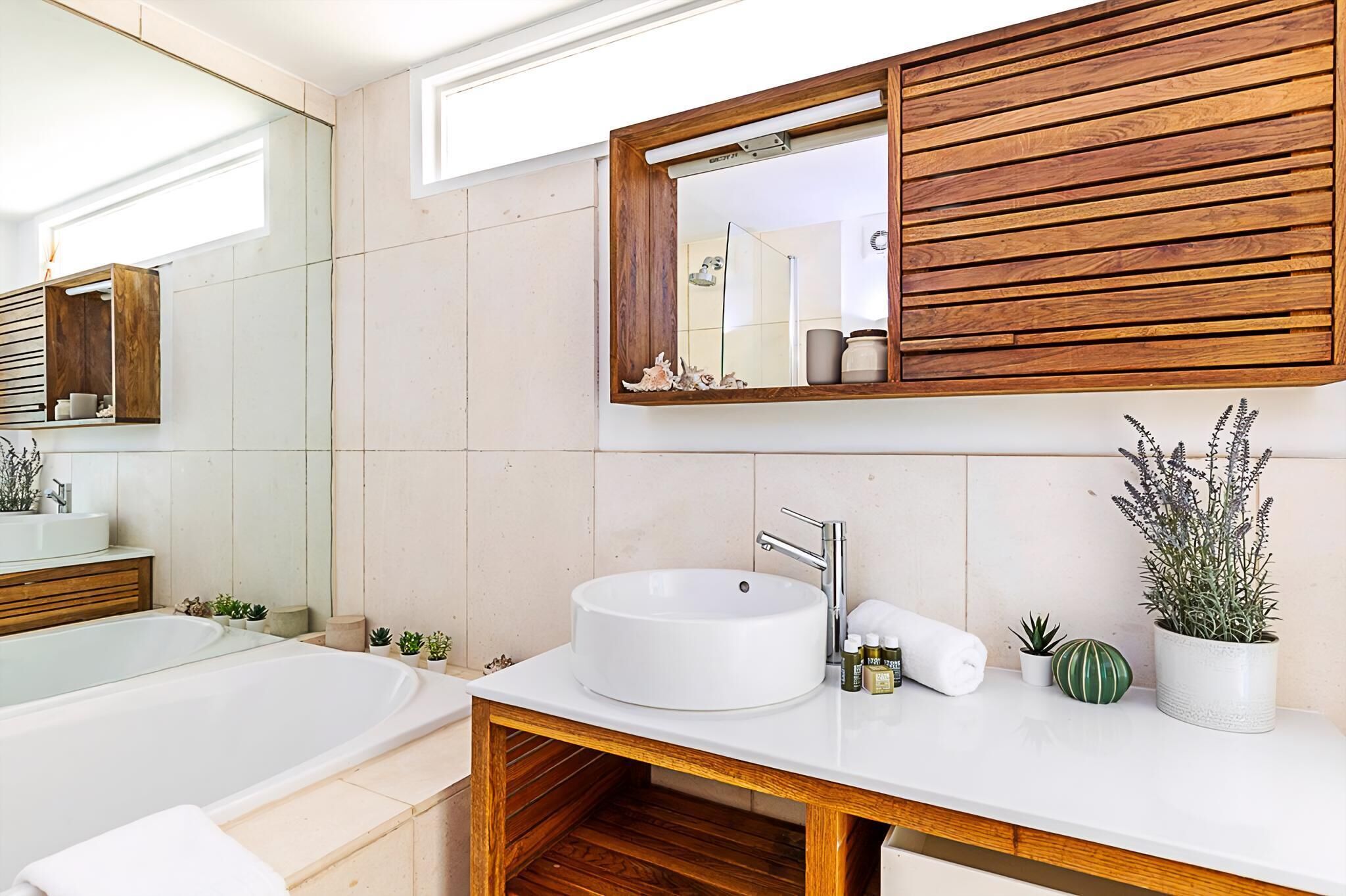 A modern bathroom with a freestanding bathtub, a white sink with a wooden vanity, and a mirror with a wooden frame.