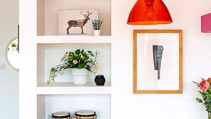 A wall with shelves displaying a deer print, a potted plant, and a framed picture.