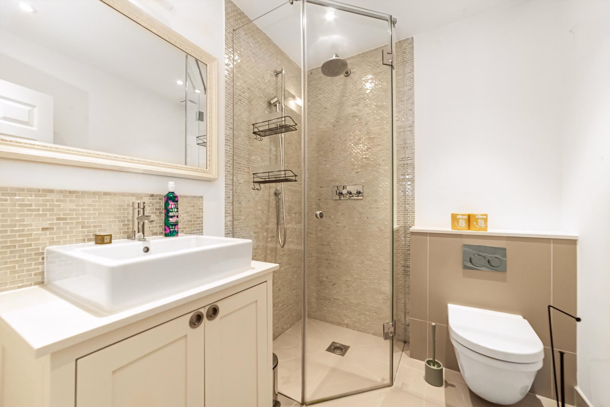 Un baño moderno con ducha acristalada, lavabo blanco y retrete.