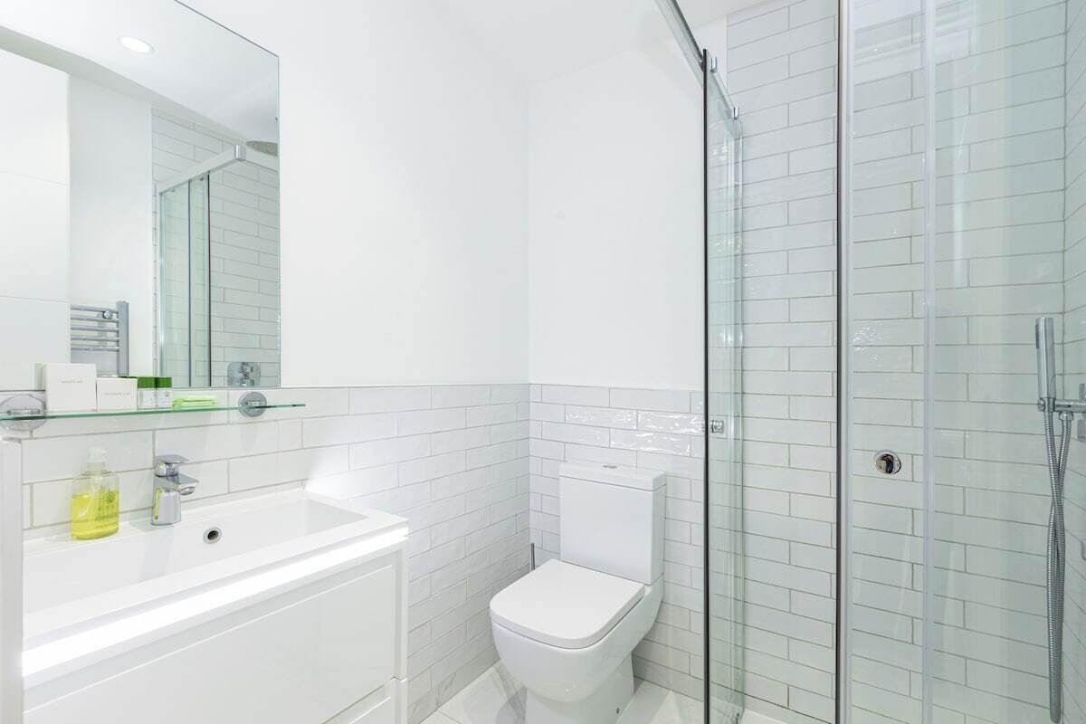 Une salle de bain moderne avec une douche à parois de verre, un lavabo blanc et des toilettes.