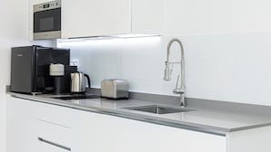 Una cocina moderna con cafetera incorporada, tostadora y pileta de acero inoxidable.