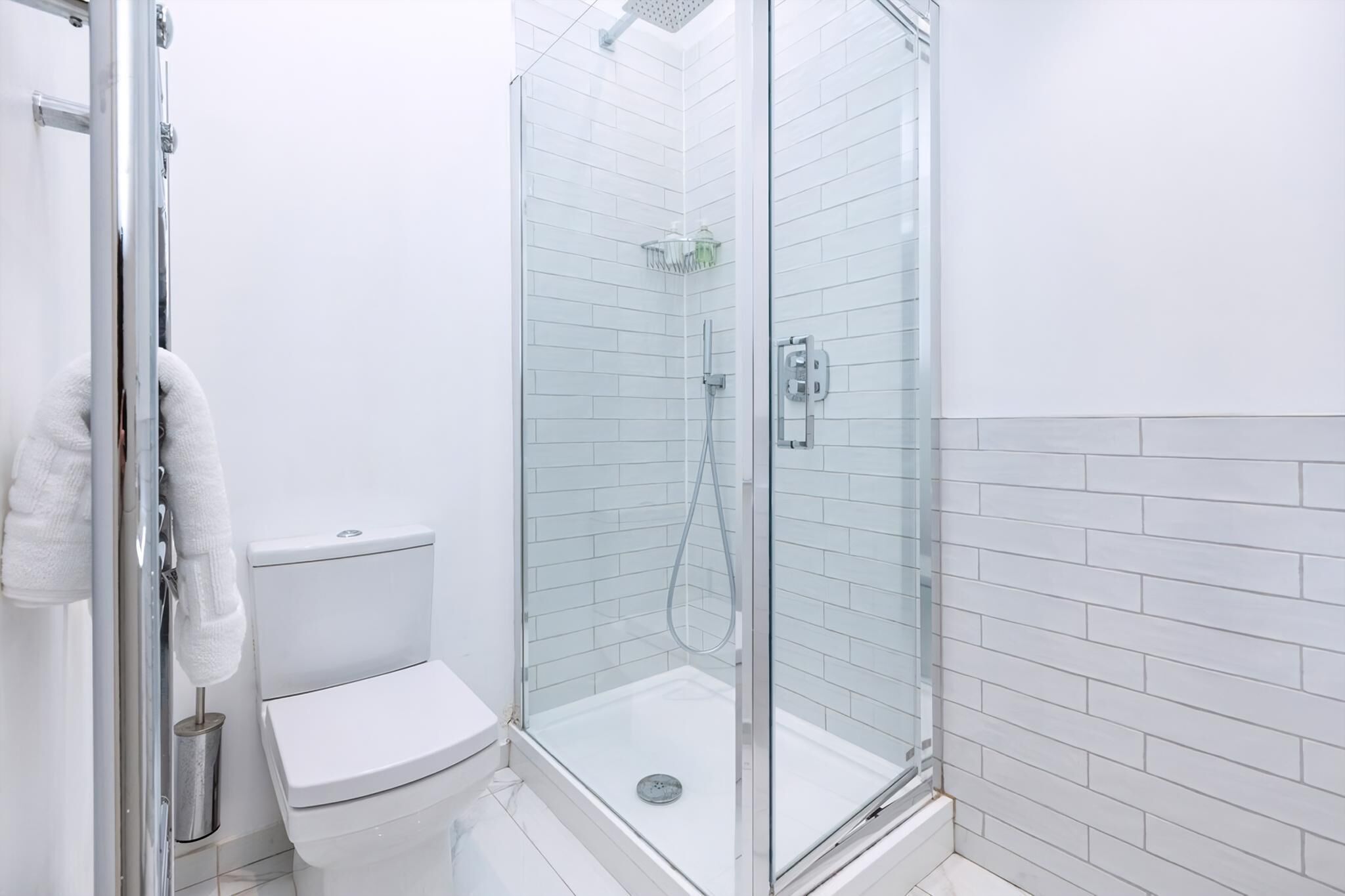 A modern bathroom with a glass-enclosed shower, a toilet, and a glass shower door.
