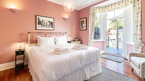 Une chambre à coucher avec un grand lit, une table de chevet, une lampe et une fenêtre avec des rideaux.