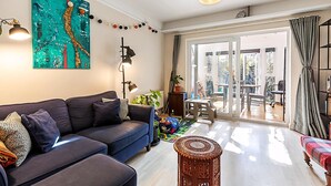 Un salon moderne avec un canapé bleu foncé, un grand tableau abstrait et un coin repas comprenant une table et des chaises.