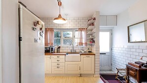 Une cuisine avec des meubles blancs, un plan de travail en bois, un évier et un luminaire suspendu.