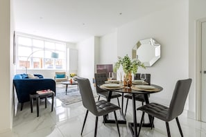 Uma sala de jantar moderna com uma mesa redonda, cadeiras pretas e um espelho grande na parede.