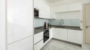 Eine moderne Küche mit weißen Schränken, einem Edelstahlbackofen und einer schwarzen Arbeitsplatte.