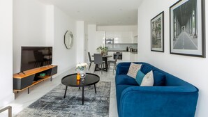 Ein modernes Wohnzimmer mit einem blauen Sofa, einem Couchtisch und einem Flachbildfernseher.