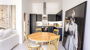 Een moderne keuken met donkere kastjes, een roestvrijstalen afzuigkap en een houten eettafel met stoelen.