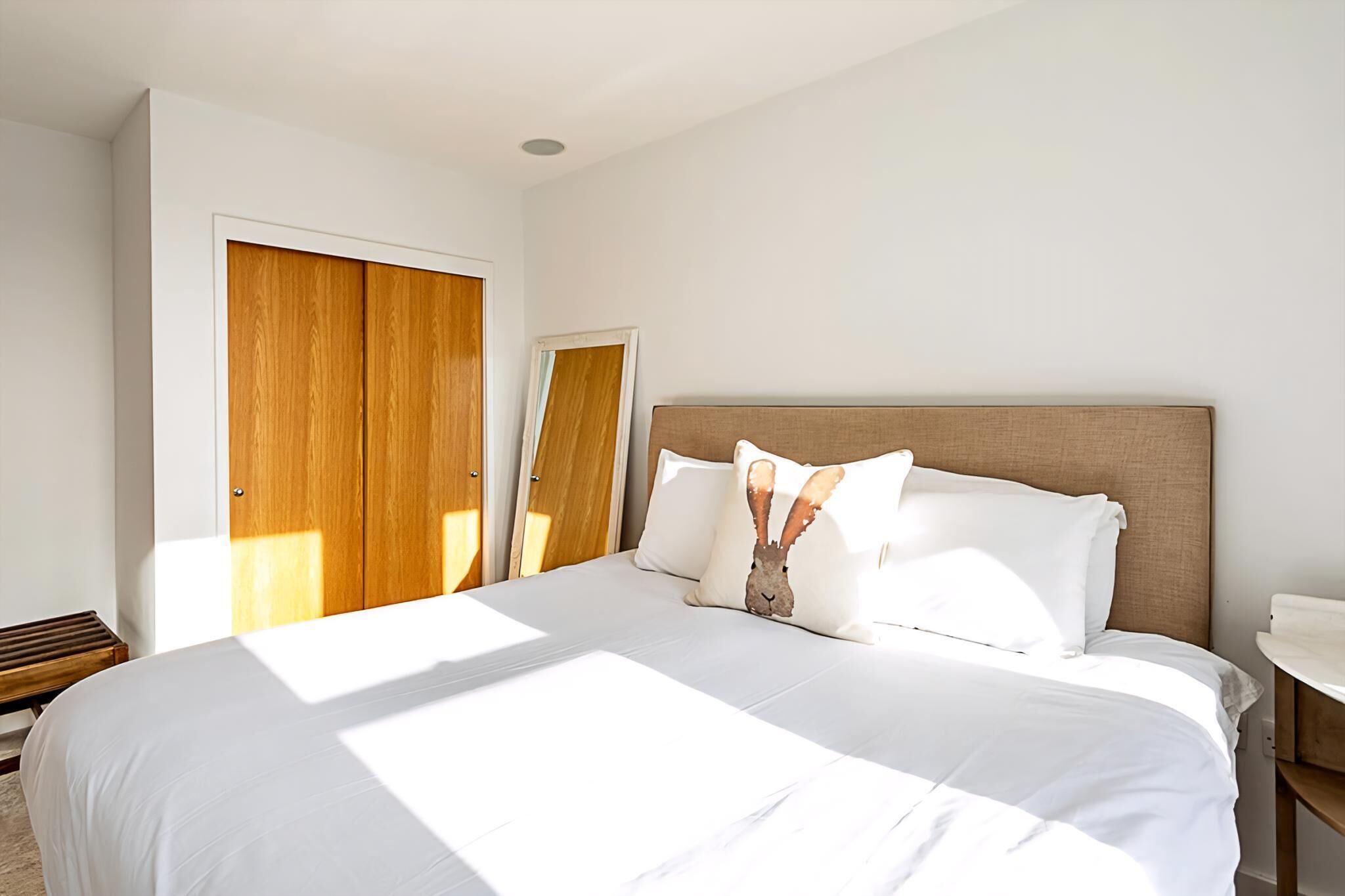 A hotel room with a large bed, wooden wardrobe, and a small bedside table.