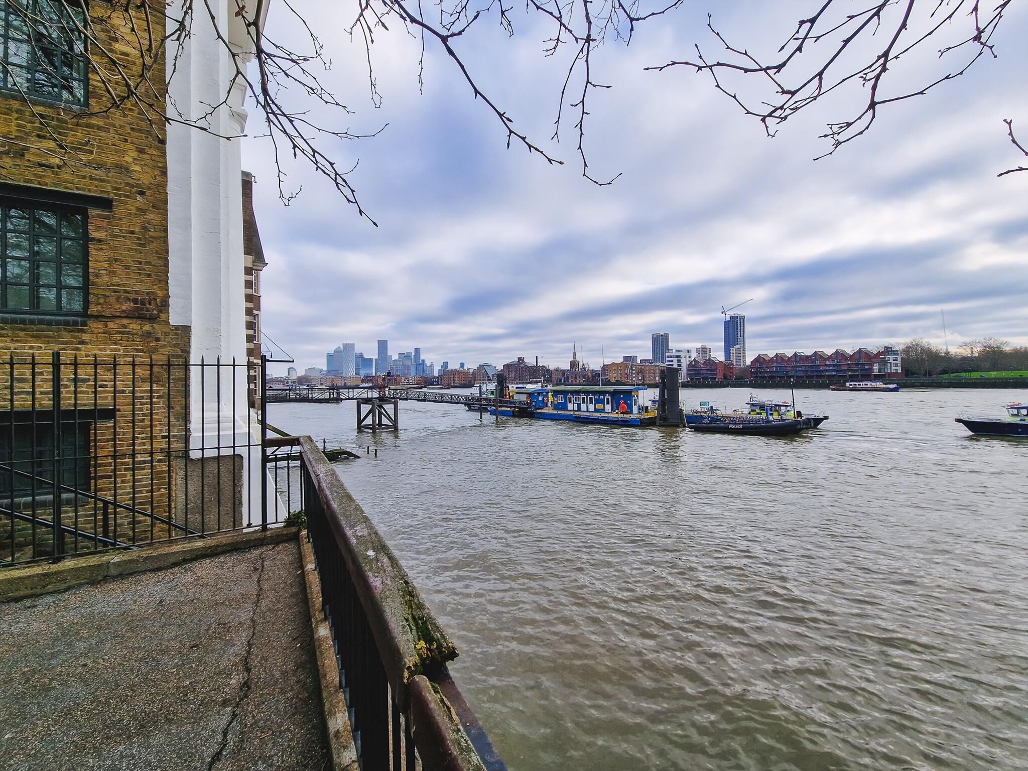 A riverside view with a bridge, boats, and a city skyline in the background.