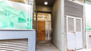 A narrow entrance with a wooden door marked '21 THE SPACE WORKS,' a metal shutter door, and a textured wall. - The Spaceworks Stylish Flat Near Shoreditch (London)