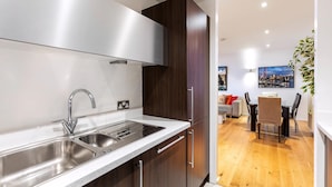 A modern kitchen with stainless steel appliances, wooden cabinets, and a dining area with a table and chairs. - The Spaceworks Stylish Flat Near Shoreditch (London)