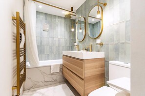 A modern bathroom with a bathtub, a vanity with a mirror, and a toilet. - Unique and Stylish 2-bed Maisonette in Islington (London)