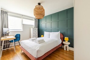 A neatly arranged bedroom with a bed, desk, chair, and bedside lamps. - Unique and Stylish 2-bed Maisonette in Islington (London)