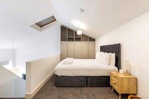 Une chambre à coucher moderne avec un lit, une table de chevet et des rangements intégrés.