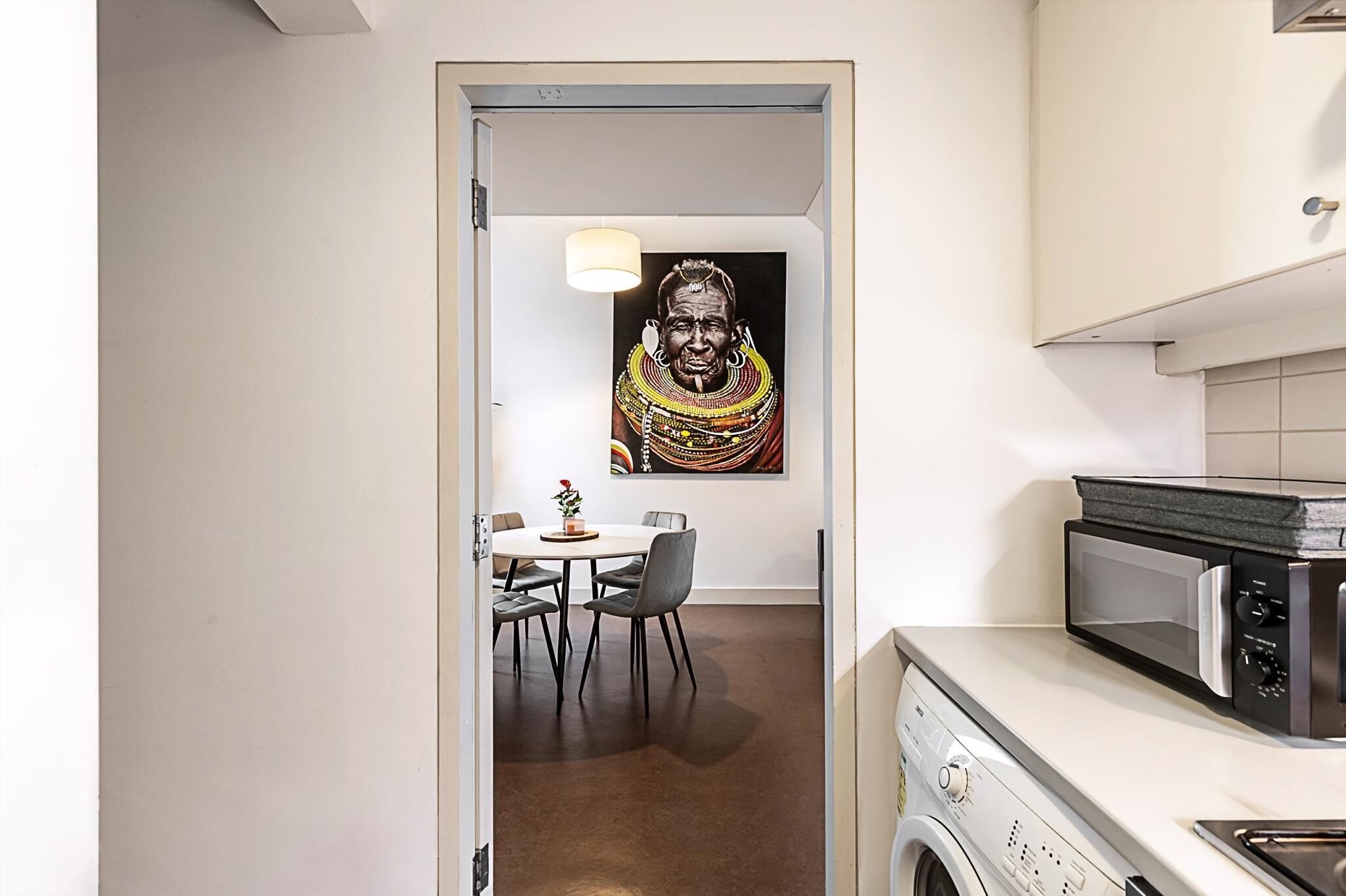 Une cuisine moderne équipée d’un four à micro-ondes, d’un lave-linge et d’un coin repas avec une table et des chaises.