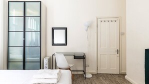 Une chambre à coucher comprenant un lit, un bureau, une chaise, un radiateur et une armoire.