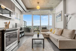 Un apartamento moderno con cocina, sala de estar y ventanas amplias que dan a una vista de la ciudad.
