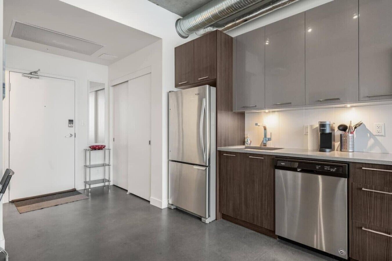 Una cocina moderna con electrodomésticos de acero inoxidable, armarios de madera y lavavajillas.