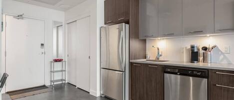 Una cocina moderna con electrodomésticos de acero inoxidable, armarios de madera y lavavajillas.