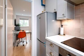 Una cocina moderna con un refrigerador empotrado, una encimera con estufa y una silla.