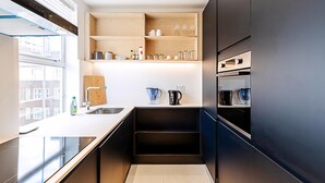 Eine moderne Küche mit Einbauofen, Spüle und Holzregalen.