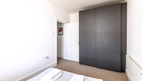 Ein Hotelzimmer mit einem Bett, einem Schrank und einer Tür zu einem weiteren Raum.