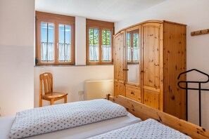 Ein Schlafzimmer mit zwei Betten, einem Holzschrank, einem Stuhl und einer Heizung.
