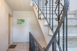 Eine Treppe mit Metallgeländer, eine Tür am Fußende und ein an der Wand befestigtes Bild.