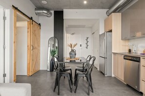 Een moderne keuken met een eethoek, met een grote tafel, stoelen en roestvrijstalen apparatuur.