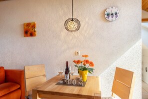 A dining area with a wooden table, a vase of flowers, a wine bottle, and glasses.