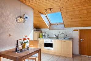 A kitchen with wooden cabinets, a stove, a sink, and a skylight.