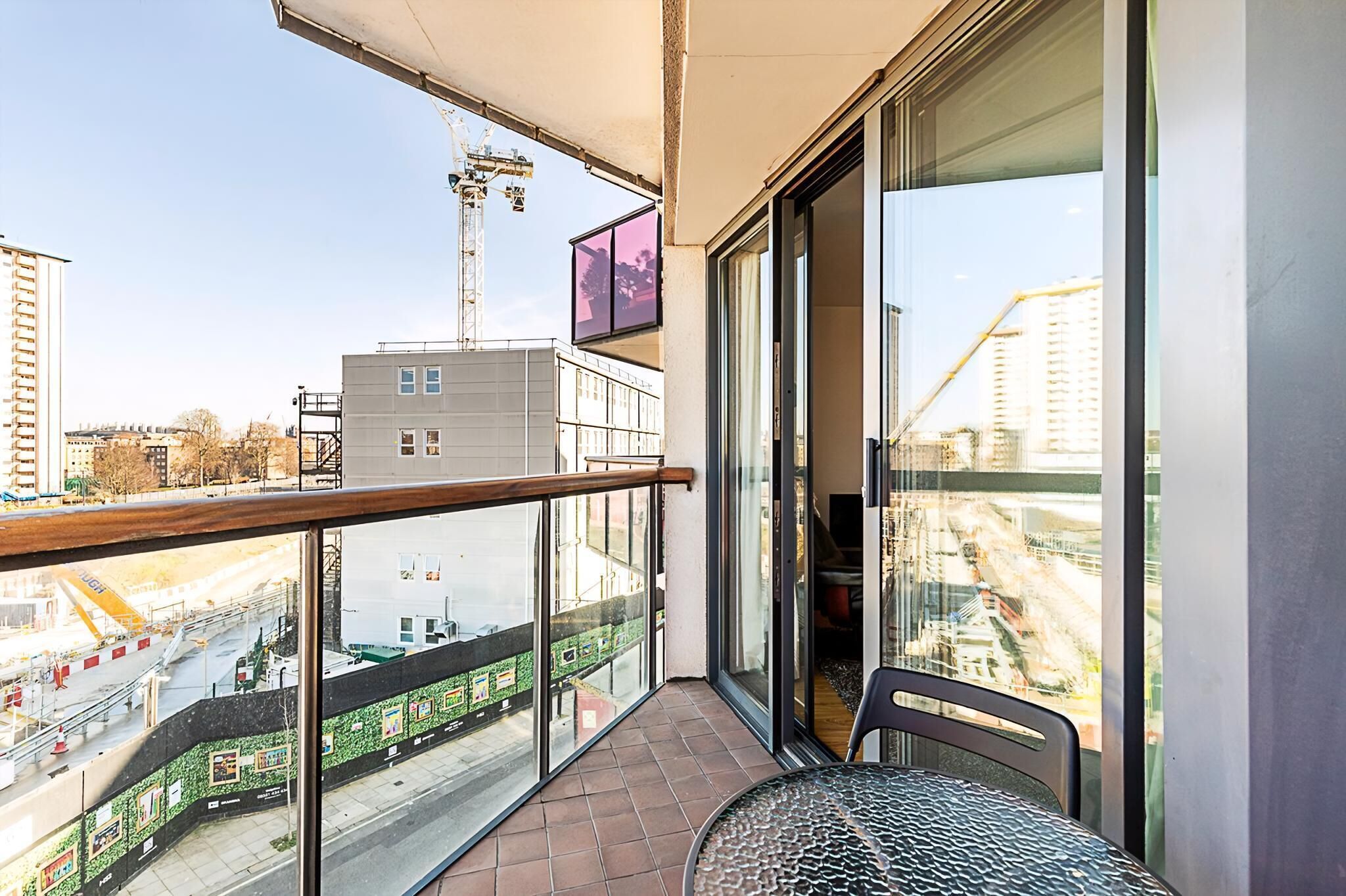 A balcony with a glass door, a chair, and a view of a construction site.