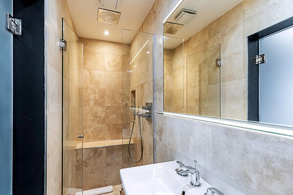 A modern bathroom with a glass-enclosed shower, a white sink, and a large mirror. - Stylish Shepherd's Bush Flat With Patio (London)