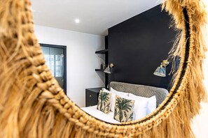 Une chambre à coucher comprenant un lit, une table de chevet, un miroir et un meuble mural.