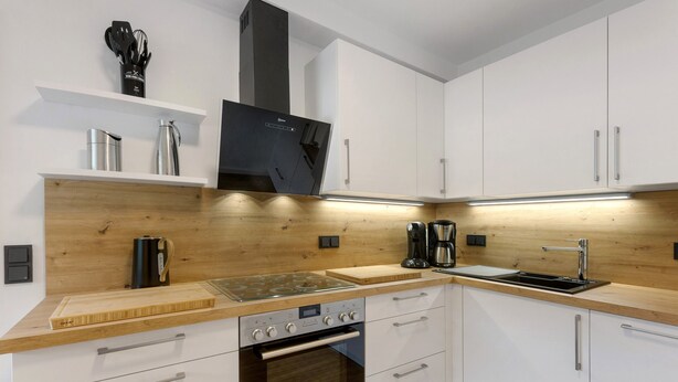 A modern kitchen with white cabinets, a wooden countertop, stainless steel appliances, and a built-in oven. - Holiday Apartment 'Schwalbennest' with Mountain View, Private Terrace and Wi-Fi (Lennestadt)