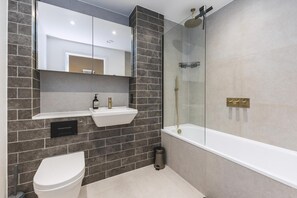 Uma casa de banho moderna com lavatório branco, sanita e cabine de duche em vidro.