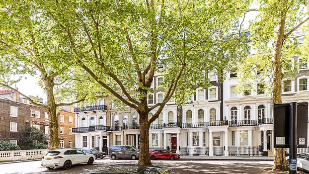 A tree-lined street with parked cars and a row of white buildings with balconies. - Elegant Knightsbridge Flat Near Harrods (London)