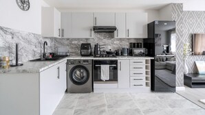 A modern kitchen with a built-in washer, oven, and coffee maker. - Modern South Wimbledon Stay (London)