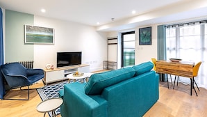 A modern living room with a sofa, TV, and dining area. - Cosy and Stylish Studio in the Heart of Greenwich (London)