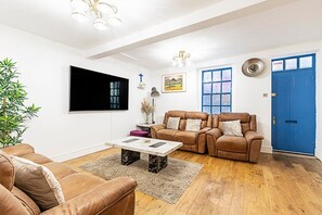 A living room with a brown leather sofa, a coffee table, and a blue door.