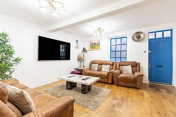 A living room with a brown leather sofa, a coffee table, and a blue door.