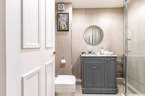 Une salle de bain comprenant des toilettes, un meuble-lavabo avec un miroir et un espace douche.