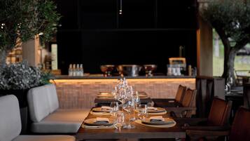 A restaurant with a long dining table set for a meal, surrounded by cushioned seating.