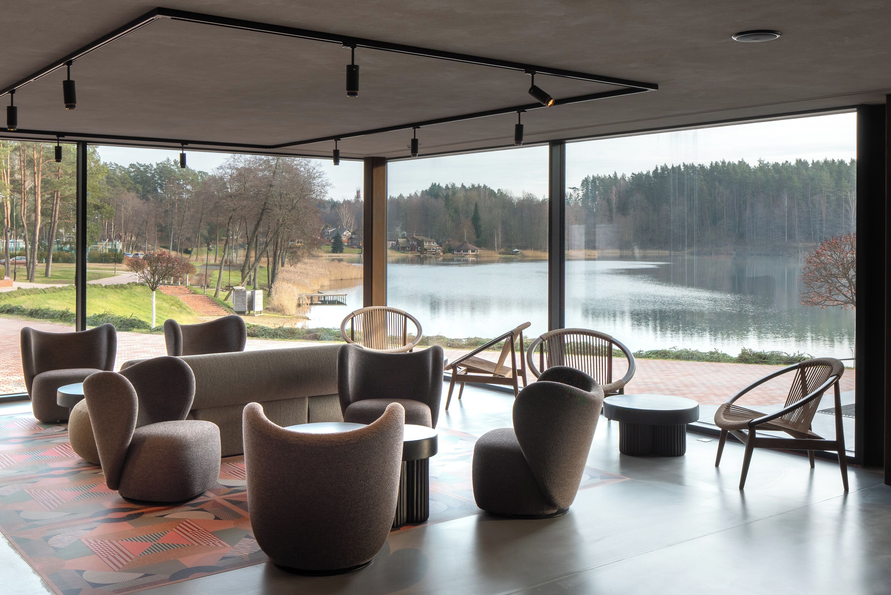 Un interior moderno con amplios ventanales que dan a un lago y un bosque.