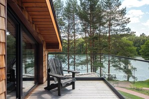 A wooden deck with a bench overlooking a lake, surrounded by trees. - Esperanza Lake Resort a Member of Design Hotels (Trakai)