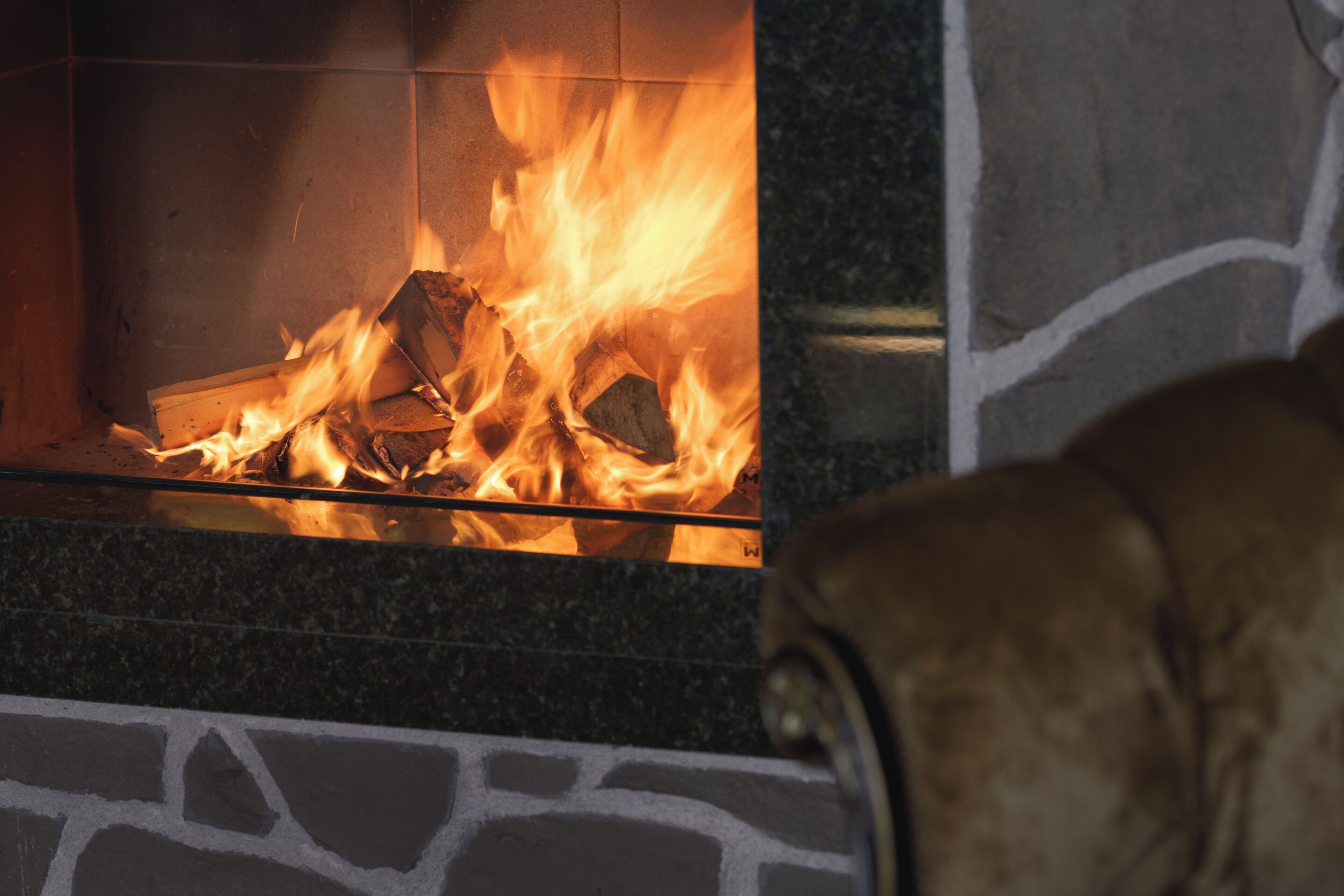 A fireplace with a visible fire burning logs.