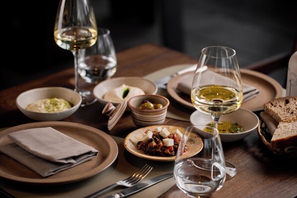 A dining table with various dishes, glasses of white wine, and bread. - Esperanza Lake Resort a Member of Design Hotels (Trakai)